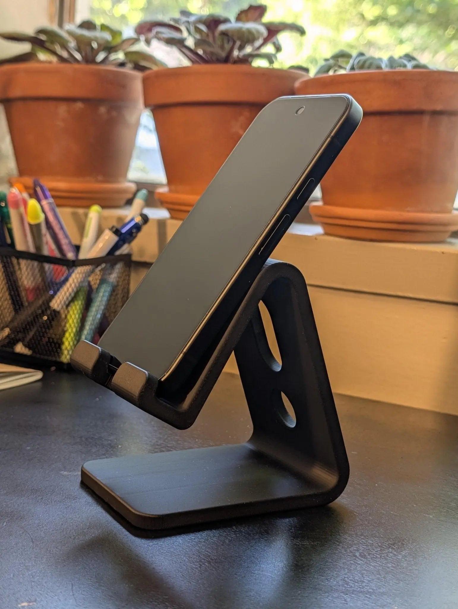 Minimalist phone stand for desk holding a smartphone, perfect for organizing cables and enhancing workspace aesthetics.
