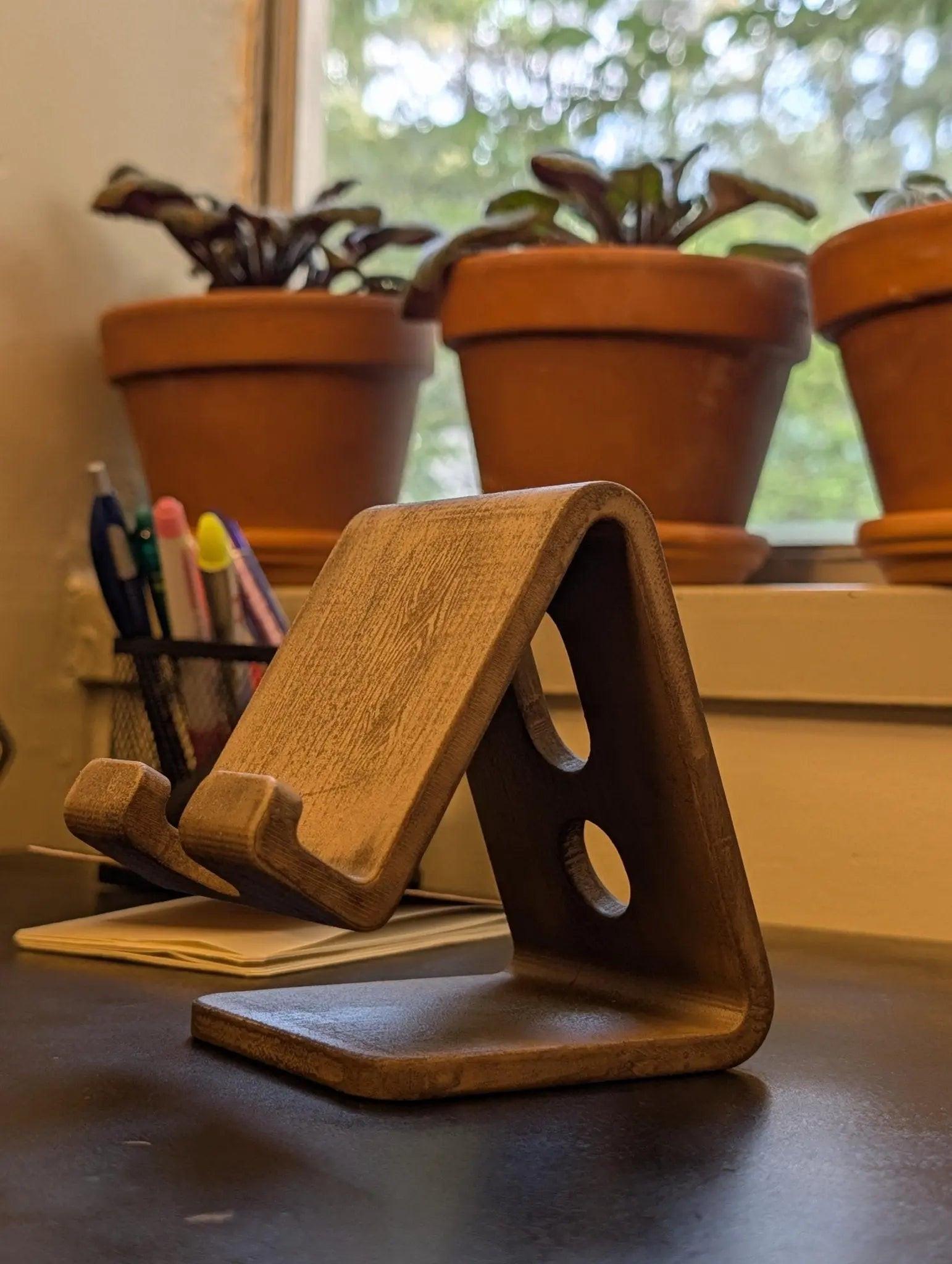 Minimalist phone stand for desk with cable organizer features, ideal for smartphones in a stylish office environment.